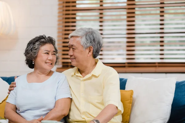 Ein älteres asiatisches Paar hält sich im Wohnzimmer an den Händen, ein Paar, das sich glücklich teilt und sich gegenseitig unterstützt, wenn es zu Hause auf dem Sofa liegt. Lifestyle Seniorenfamilie zu Hause Konzept. — Stockfoto