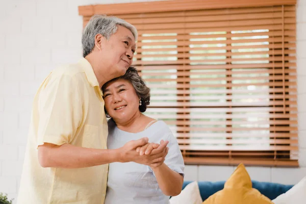 Asiatisches älteres Paar tanzt zusammen, während es zu Hause Musik im Wohnzimmer hört, süßes Paar genießt den Moment der Liebe, während es zu Hause entspannt Spaß hat. Lifestyle Senioren Familie entspannen zu Hause Konzept. — Stockfoto