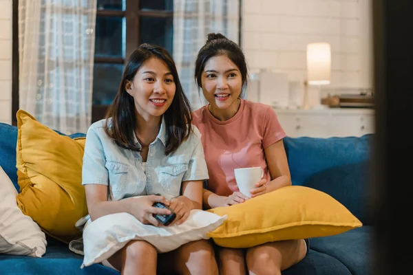 Lesbisk hbt kvinnor par tittar på TV hemma, Asiatisk kvinnlig älskare känsla glad rolig stund ser drama underhållning tillsammans på soffan i vardagsrummet i natt koncept. — Stockfoto