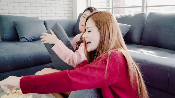 Femmes asiatiques jouant bataille d'oreillers et manger du pop-corn dans le salon à la maison, groupe de colocataire ami profiter moment drôle tout en étant allongé sur le canapé. Lifestyle femmes se détendre à la maison concept . — Photo