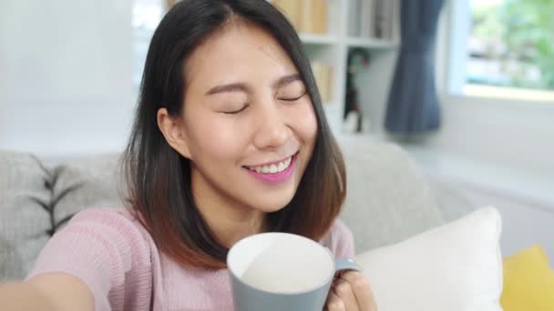 年轻的亚洲少女在家里大吵大闹 女人们喝咖啡 用智能手机在客厅里给社交媒体制作Vlog视频 生活方式的女人早上在家休息一下 — 图库视频影像