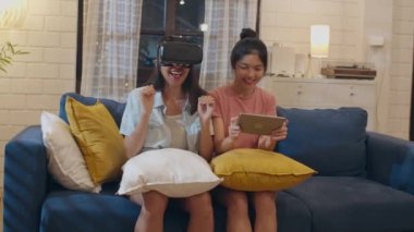 Lezbiyen lgbt kadın çift evde tablet kullanarak, Asyalı kadın gece oturma odasında kanepe yatarken birlikte oyun oynarken dizüstü bilgisayar ve Vr kullanarak mutlu hissediyorum. Lover tatil konsepti kutlamak.