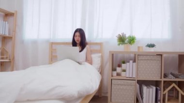 Genç iş serbest Asyalı kadın evde yatak odasında dinlenmek yatakta yatarken sosyal medya kontrol dizüstü çalışan. Ev konseptinde yaşam tarzı kadınlar.