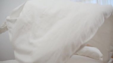 Asyalı kadın yatak odasında yatağını temizleyerek, Güzel Japon kadın kurmak ve evde yatak battaniye yapma. Yaşam tarzı kadınlar ev konsepti temizlik zaman kullanarak. Yavaş çekim çekimi.