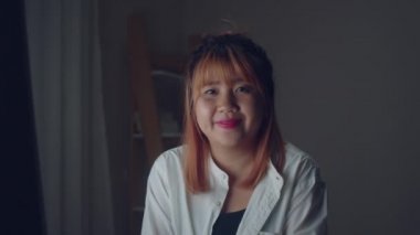 Genç Asyalı yaratıcı kadın evde gülümsüyor. İş kadın mutlu gece geç mesai işten sonra dinlenmek, kamera, iş durumu, ev ofis kavramı son tarih arıyorum.