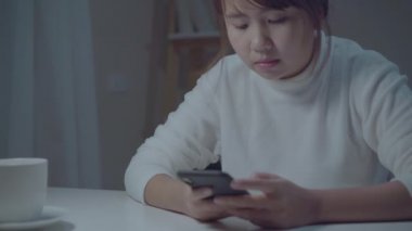 Genç Asyalı kadın evde cep telefonu kullanıyor. kadın uykusuzluk sıkılmış ve yorgun gece işten sonra sosyal medya kontrol ederken, uykudan önce, genç oyun teknolojisi kavramı.