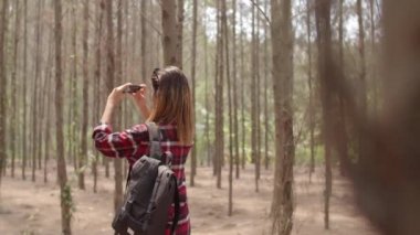 Asyalı yürüyüşçü kadın ormanda trekking. Telefon kullanarak genç mutlu sırt çantası kız seyahat doğa ve macera gezisi sırasında fotoğraf çekmek, yaz tatilleri tatil konsepti dağa tırmanmak. Yavaş çekim.