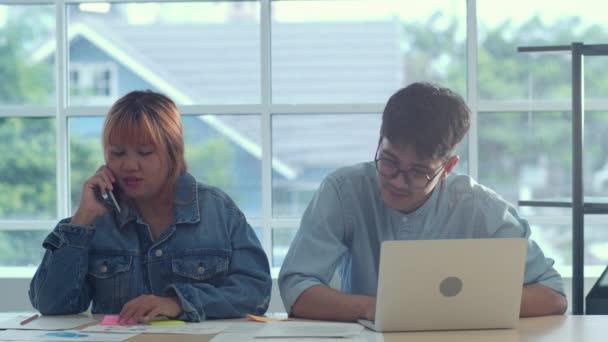 年轻的亚洲创意团队会议工作在笔记本电脑 集团男女用手机与客户交谈 业务情况 团队合作在现代办公理念 慢动作 — 图库视频影像