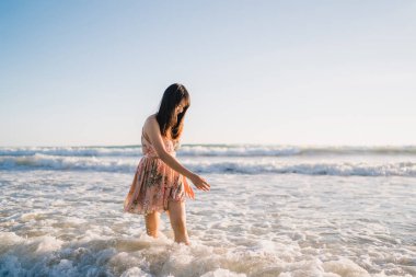 Sahilde yürüyen genç Asyalı kadın. Güzel kadın mutlu akşam gün batımı nda deniz kenarında sahilde yürüyüş rahatlayın. Yaşam tarzı kadın plaj konsepti seyahat.