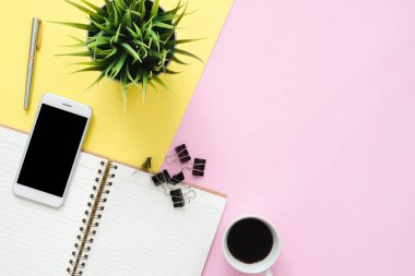 Ofis Masası adlı kullanıcının alanı - düz çalışma beyaz boş defter sayfası, kahve fincanı ve sahte telefon pastel arka plan üzerinde bir çalışma alanının en iyi görünümü yatırın. Pastel pembe sarı renk arka plan boşluk kavramı.
