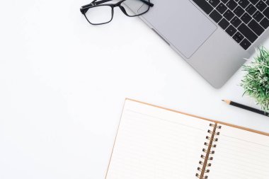 Yaratıcı düz Fotoğraf çalışma masası yatıyordu. Üstten görünüm ofis büro dizüstü bilgisayar, Gözlük, kalem, defter ve beyaz renk arka plan üzerinde bitki. Kopya alanı, düz yatıyordu fotoğraf ile üstten görünüm.