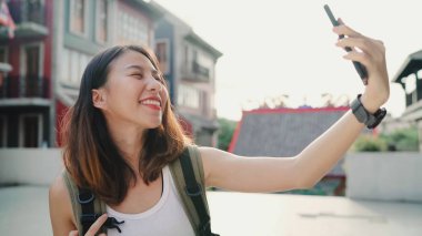 Beijing, Çin mahallesinde, seyahat ederken selfie alarak smartphone kullanan neşeli güzel genç Asyalı backpacker blogger kadın. Yaşam tarzı sırt çantası turizm seyahat tatil kavramı.