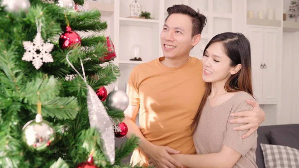 Couple asiatique se sentent heureux de décorer l'arbre de Noël dans leur salon à la maison dans le festival de Noël. Lifestyle femme et homme heureux célébrer Noël d'été et concept de nouvelle année . — Photo
