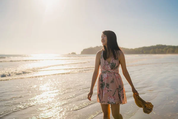 Jovem mulher asiática andando na praia. Bela fêmea feliz relaxar andando na praia perto do mar quando o pôr do sol à noite. Estilo de vida as mulheres viajam no conceito de praia . — Fotografia de Stock