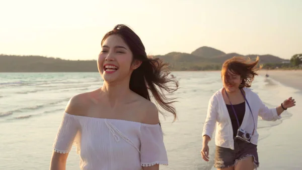 Junge asiatische lesbische Paar läuft am Strand. schöne Freundinnen glücklich entspannen und Spaß am Strand in der Nähe des Meeres haben, wenn der Sonnenuntergang am Abend. Lifestyle lesbisches Paar reist am Strand Konzept. — Stockfoto