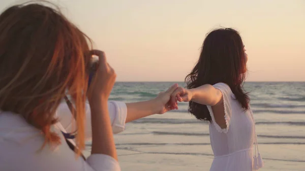 Jovem casal lésbico asiático usando câmera tirando foto uns aos outros perto da praia. Mulheres bonitas lgbt casal feliz momento romântico quando o sol se põe à noite. Estilo de vida casal lésbico viajar no conceito de praia . — Fotografia de Stock