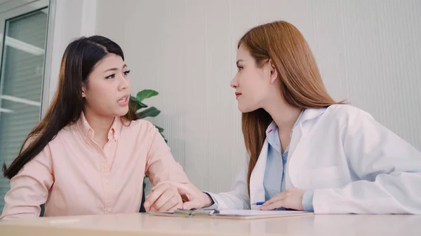 Doutor falando com paciente adolescente infeliz na sala de exames. Mulher asiática médico encorajamento e apoio ao paciente com câncer após consultar e examinar a saúde na clínica médica ou hospital . — Fotografia de Stock