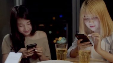Bir grup Asyalı kadın evde parti, kadın gece oturma odasında sosyal medya kontrol cep telefonu kullanarak bira içme. Genç genç arkadaş oyun, dostluk, tatil kutlamak. Yavaş çekim.