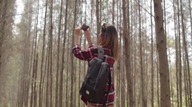 Asyalı yürüyüşçü kadın ormanda trekking. Telefon kullanarak genç mutlu sırt çantası kız seyahat doğa ve macera gezisi sırasında fotoğraf çekmek, yaz tatilleri tatil konsepti dağa tırmanmak. Yavaş çekim.