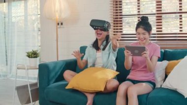 Genç Lezbiyen lgbtq Asyalı kadın çift evde tablet kullanarak, Asyalı sevgilisi kadın duygu mutlu eğlence ve sanal gerçeklik, Vr evde oturma odasında kanepeydeyken birlikte oyun oynarken kavramı.