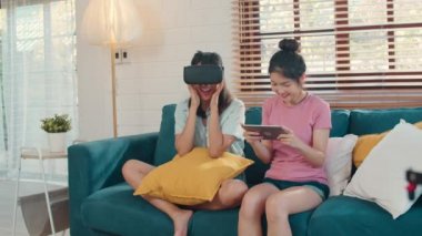 Genç Lezbiyen lgbtq Asyalı kadın çift evde tablet kullanarak, Asyalı sevgilisi kadın mutlu eğlence ve sanal gerçeklik hissi, Vr oturma odası kavramı kanepe yatarken birlikte oyun oynarken. Yavaş çekim.