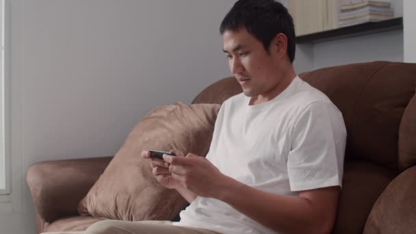 Ung Asiatisk Man Med Mobiltelefon Spelar Spel Vardagsrummet Manliga Känner — Stockvideo