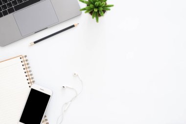 Yaratıcı düz Fotoğraf çalışma masası yatıyordu. Üstten görünüm ofis büro dizüstü bilgisayar, telefon, kalem, defter ve beyaz renk arka plan üzerinde bitki. Kopya alanı, düz yatıyordu fotoğraf ile üstten görünüm.