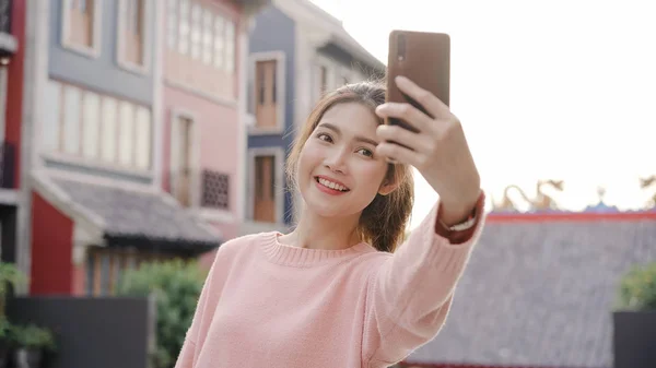 Munter, vakker ung asiatisk backpacker-blogger som bruker smarttelefon som tar selfie mens hun reiser i Chinatown i Beijing, Kina. Livsstilsryggsekkturismebegrepet feriereise . – stockfoto