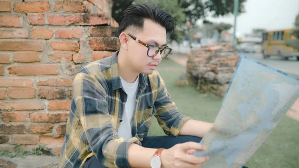 Traveler Asian man direction and looking on location map while spending holiday trip at Ayutthaya, Thailand, backpacker male enjoy journey in traditional city. Estilo de vida homens viagem conceito . — Fotografia de Stock