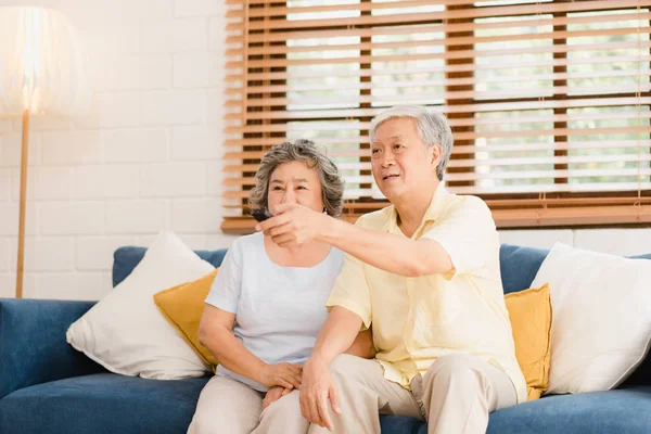 Asiatisches älteres Paar vor dem Fernseher im Wohnzimmer zu Hause, süßes Paar genießen Liebesmomente, während sie zu Hause entspannt auf dem Sofa liegen. Zeit genießen Lebensstil Familie zu Hause Konzept. — Stockfoto