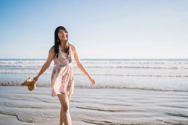 Jovem mulher asiática andando na praia. Bela fêmea feliz relaxar andando na praia perto do mar quando o pôr do sol à noite. Estilo de vida as mulheres viajam no conceito de praia . — Fotografia de Stock