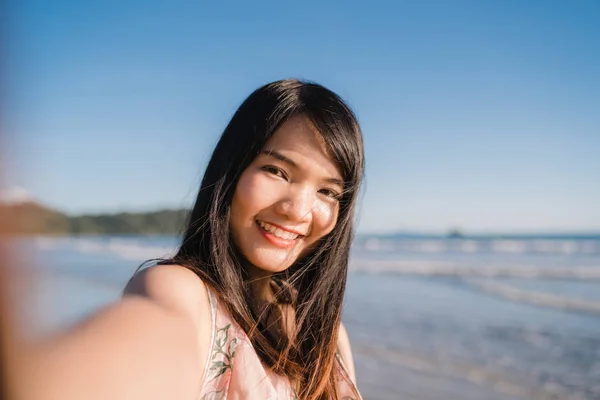 해변에서 관광 아시아 여자 셀카, 젊은 아름 다운 여성 행복 미소 저녁에 일몰 때 바다 근처 해변에서 셀카를 복용 하는 휴대 전화를 사용 하 여. 라이프 스타일 여성은 해변 개념에 여행. — 스톡 사진