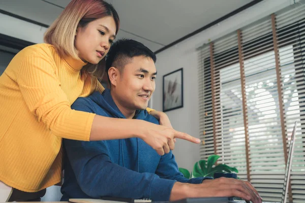 Nuori aasialainen pari, joka hallinnoi taloutta, tarkistaa pankkitilinsä kannettavan tietokoneen ja laskimen avulla nykyaikaisessa kodissa. Nainen ja mies tekevät paperityötä yhdessä, maksaa veroja verkossa kannettavan tietokoneen . — kuvapankkivalokuva