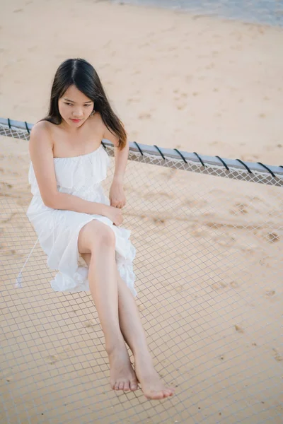 Jovem mulher asiática sentada na rede relaxar na praia, bela fêmea feliz relaxar perto do mar. Estilo de vida as mulheres viajam no conceito de praia . — Fotografia de Stock