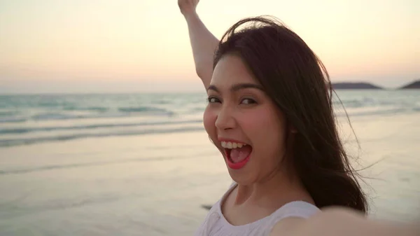 Tourist Asian woman selfie on beach, young beautiful female happy smiling using mobile phone taking selfie on beach near sea when sunset in evening. Lifestyle women travel on beach concept. — Stock Photo, Image