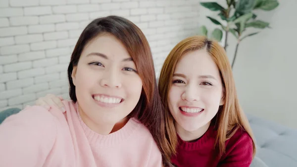 Las mujeres blogueras asiáticas usando selfie de teléfonos inteligentes y grabando video vlog en la sala de estar en casa, grupo de amigos disfrutan de momentos divertidos mientras están tumbadas en el sofá cuando se relajan en casa. Punto de vista . —  Fotos de Stock