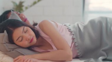 Asyalı Lezbiyen lgbtq kadın çift evde uyanmak. Genç Asya sevgilisi kadın mutlu sabah kavramı evde yatak odasında yatakta yatarken tüm gece uyuduktan sonra birlikte dinlenmek. Yavaş çekim.
