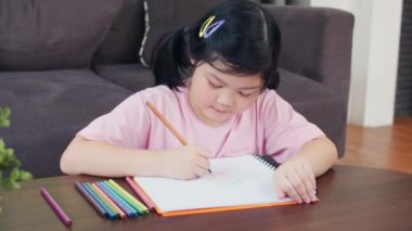 Genç Asyalı kız evde çizim. Asya japon kadın çocuk çocuk dinlenmek dinlenmek eğlenceli kanepeüzerinde yatan sketchbook karikatür çizmek mutlu çizmek, sabah kavramı oturma odasında rahatlık ve sakin hissediyorum. Yavaş çekim.