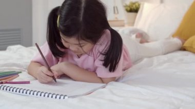 Genç Asyalı kız evde resim çiziyor. Asyalı kadın Japon çocuk rahatla dinlen eğlen çizim defterine çizgi film çiz yatağa yatmadan önce, yatak odasında rahatla ve sakinleş gece konseptinde.