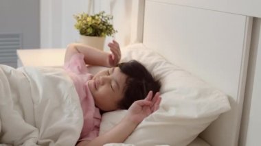 Genç Asyalı kız evde uyanmak. Asya japon kadın çocuk çocuk uykudan sonra tüm gece yatakta yatarken dinlenmek, sabah kavramı evde yatak odasında rahatlık ve sakin hissediyorum. Yavaş çekim çekimi.