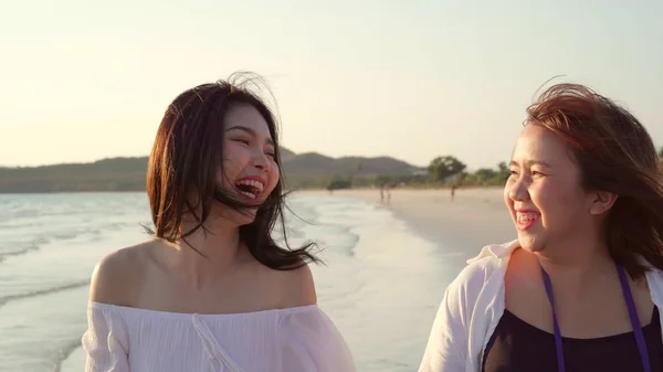 Joven pareja lesbiana asiática caminando en la playa. Hermosas mujeres amigas felices relajarse caminando en la playa cerca del mar al atardecer en la noche. Estilo de vida lesbiana pareja viajar en playa concepto . —  Fotos de Stock