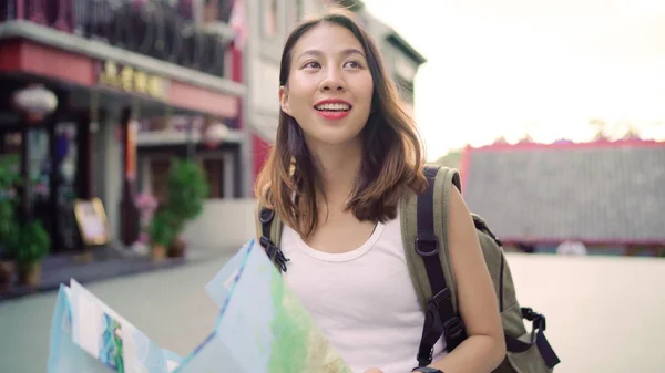 Fröhlich schöne junge asiatische Backpacker Frau Richtung und Blick auf Lageplan während der Reise in China Chinatown in Peking, China. Lifestyle Rucksack touristisches Reisekonzept. — Stockfoto