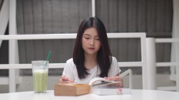 Asian student women reading books in library at university. Young undergraduate girl do homework, read textbook, study hard for knowledge and education on lecture desk at college campus. Slow motion.