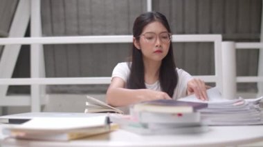 Asyalı öğrenci kadınlar üniversitede kütüphanede kitap okuyor. Genç lisans kız ev ödevi yapmak, ders kitabı okumak, üniversite kampüs kavramı ders masasında bilgi ve eğitim için çok çalışmak.