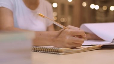 Asyalı öğrenci kadınlar üniversitede kütüphanede kitap okuyor. Genç lisans kız ev ödevi yapmak, ders kitabı okumak, üniversite kampüsünde ders masasında bilgi için çok çalışmak fazla mesai gece. Yavaş çekim.