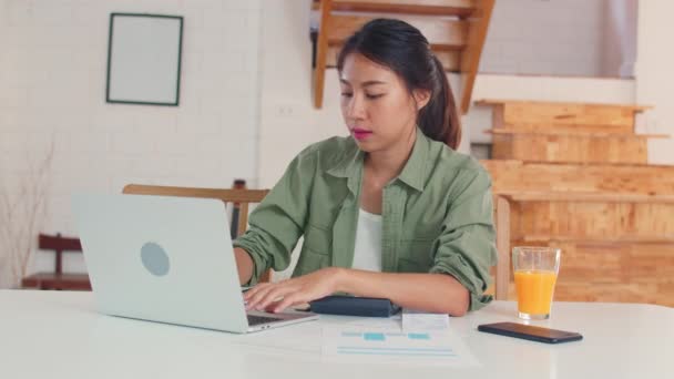 商业亚洲妇女记录收入和开支在家里 年轻的亚洲女孩快乐使用笔记本电脑记录预算 财务文件 电子商务工作在厨房的概念 — 图库视频影像