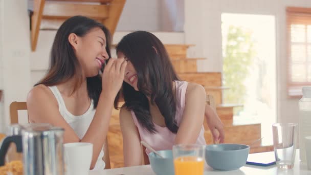 アジアのレズビアンLgbtq女性カップルは自宅で朝食を持って 若いアジアの恋人の女の子は朝のコンセプトで台所のテーブルの上にシリアルとミルクを食べながら カメラを見て幸せな歯の笑顔を感じます — ストック動画