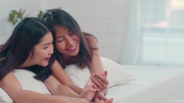 Asyalı Lezbiyen lgbtq kadın çift evde yatakta konuşurken. Genç Asya sevgilisi kadın mutlu sabah kavramı evde yatak odasında yatakta yatarken uyandıktan sonra birlikte dinlenmek. Yavaş çekim.