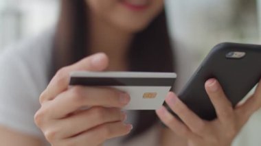 Serbest Asya kadın kahve dükkanında online alışveriş. Genç Asya Kız cep telefonu kullanarak, kredi kartı satın almak ve akşam konsepti açık kafede masada e-ticaret internet satın. Yavaş çekim.