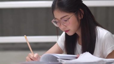 Asyalı öğrenci kadınlar üniversitede kütüphanede kitap okuyor. Genç lisans kız ev ödevi yapmak, ders kitabı okumak, üniversite kampüs kavramı ders masasında bilgi ve eğitim için çok çalışmak.
